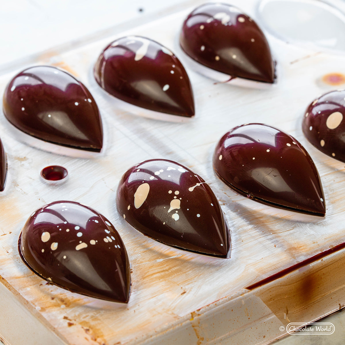 Shiny teardrop-shaped bonbons in a polycarbonate chocolate mold