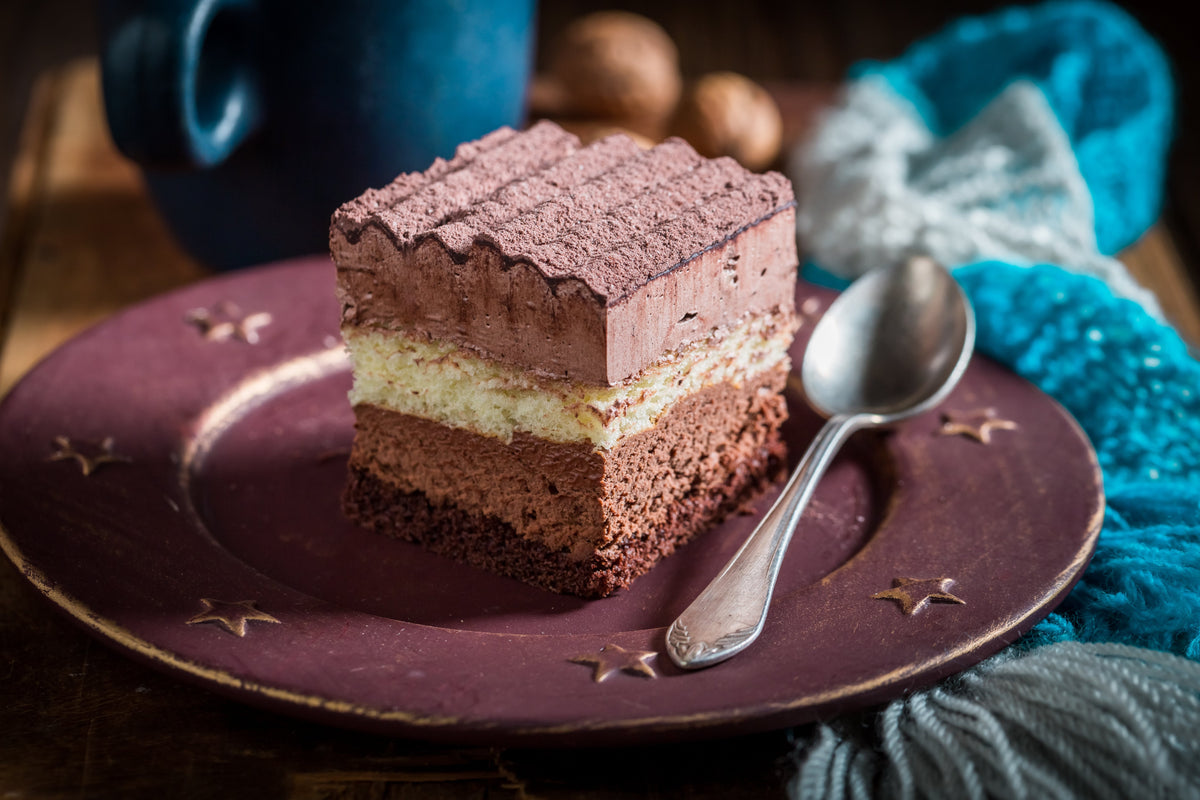 Slice of layered chocolate mousse cake on a plate with a spoon